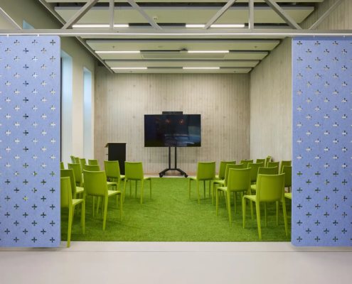 Mindlabs is een ruimte met een grasgroen tapijn, groene stoelen en een grote tv, die met blauwe panelen afgesloten kan worden.