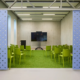 Mindlabs is een ruimte met een grasgroen tapijn, groene stoelen en een grote tv, die met blauwe panelen afgesloten kan worden.