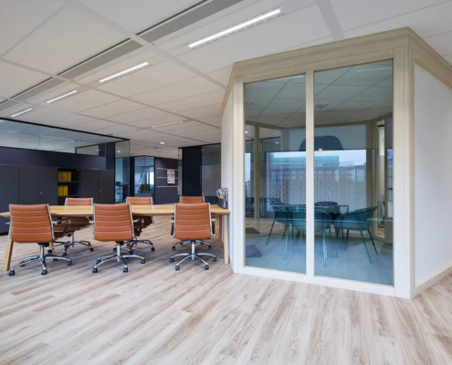 Werk- en vergaderplek met royale houten tafel bruin leren bureaustoelen.