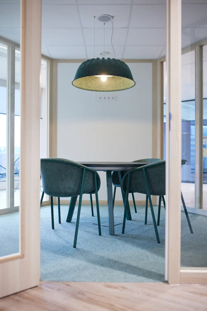 Aparte lichte ruimte met ronde tafel en stoeltjes en grote lamp boven de tafel