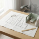 Architectonische plattegrond van een zorgkamer op een eiken bureau, met een miniatuurmaquette ernaast in zacht natuurlijk daglicht.